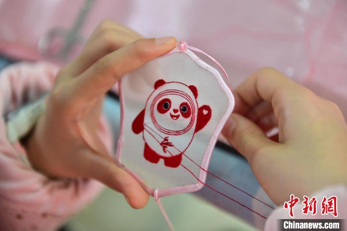 圖為一名小學(xué)生正在繡制2022年北京冬奧會(huì)吉祥物“冰墩墩”形象?！∮髟屏?攝