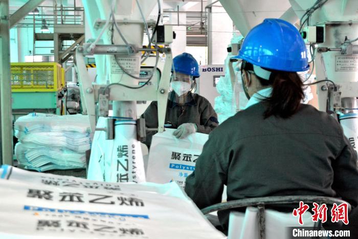 工人在生產(chǎn)線上包裝聚苯乙烯產(chǎn)品?！×趾霔v 攝