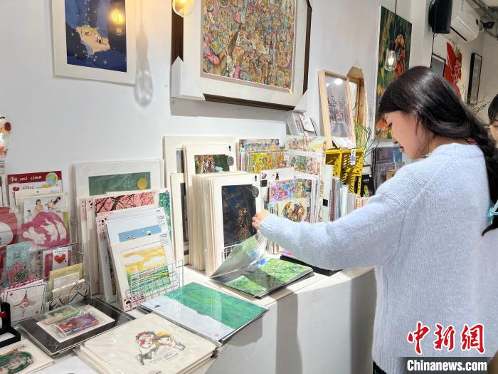 圖為藝術(shù)品商店內(nèi)，顧客挑選插畫作品?！＄婌?攝