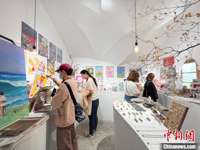 圖為藝術(shù)品商店內(nèi)，顧客挑選插畫作品?！＄婌?攝