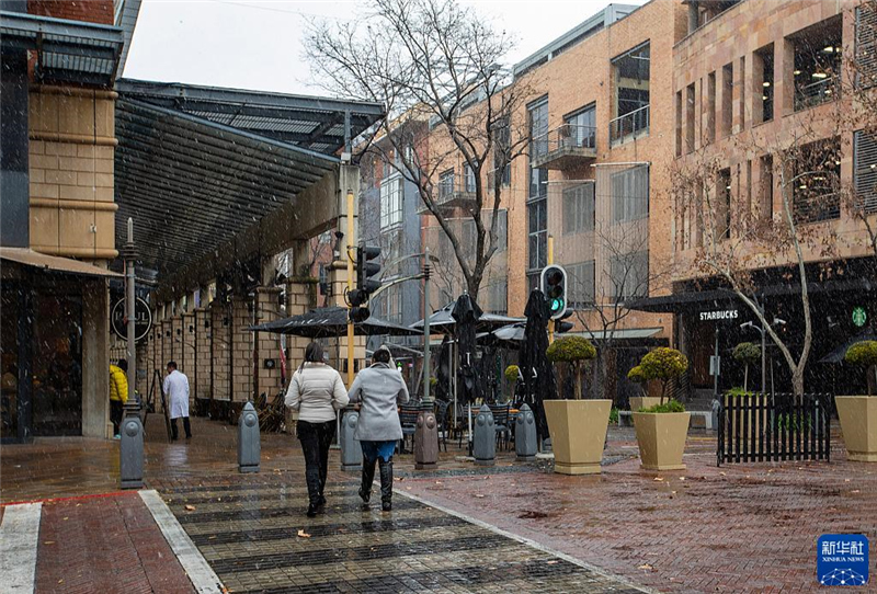 7月10日，在南非約翰內(nèi)斯堡一處商業(yè)區(qū)，人們?cè)谘┲行凶?。新華社記者 張譽(yù)東 攝