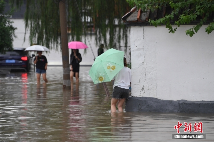 7月31日，市民行走在雨中的北京房山區(qū)瓦窯頭村。北京市氣象臺當(dāng)日10時發(fā)布分區(qū)域暴雨紅色預(yù)警信號。北京市水文總站發(fā)布洪水紅色預(yù)警，預(yù)計當(dāng)日12時至14時，房山區(qū)大石河流域?qū)⒊霈F(xiàn)紅色預(yù)警標(biāo)準(zhǔn)洪水。<a target='_blank' href='/'><p  align=