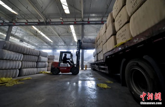 新疆喀什綜合保稅區(qū)，喀什啟路國際貿(mào)易有限公司的倉庫內(nèi)，工人正在裝載從塔吉克斯坦和烏茲別克斯坦進口的棉花。劉新攝