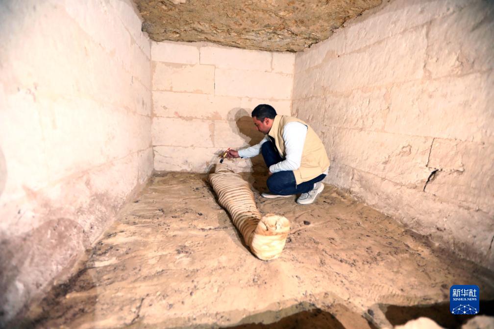 10月15日，在埃及明亞省考古現(xiàn)場(chǎng)，考古人員清理一座石鑿墓中的木乃伊。新華社發(fā)（艾哈邁德·戈馬攝）