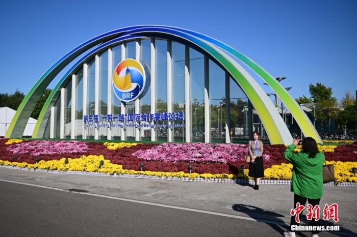 10月15日，北京，工作人員在國家會議中心外的第三屆“一帶一路”國際合作高峰論壇景觀布置前拍照留念。當(dāng)日，位于國家會議中心的第三屆“一帶一路”國際合作高峰論壇新聞中心啟動試運(yùn)行。據(jù)悉，第三屆“一帶一路”國際合作高峰論壇將于10月17日至18日在北京舉行。<a target='_blank' href='/'><p  align=