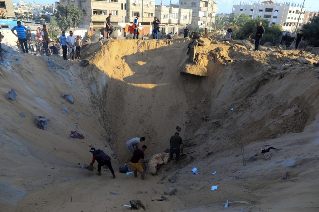 10月16日，在加沙地帶南部城市汗尤尼斯，人們在遭以色列襲擊后的建筑廢墟中救援傷者。 新華社發(fā)（亞西爾·庫迪 攝）