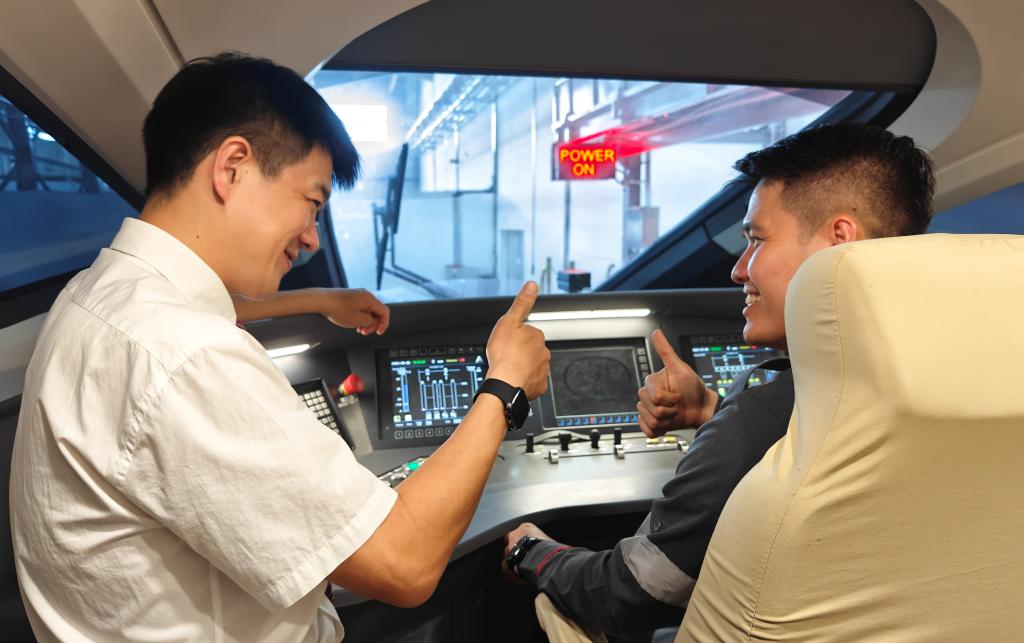 8月25日，在印度尼西亞萬隆的雅萬高鐵德卡魯爾動車所內(nèi)，中國師傅穆振（左）在向印尼火車司機塞蒂亞萬講解動車組出庫前的上電作業(yè)。