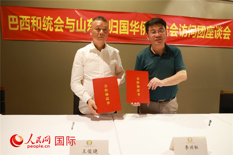 中國僑聯(lián)副主席、山東省僑聯(lián)主席李興鈺（右）與巴西和統(tǒng)會會長王俊曉簽署合作協(xié)議書。人民網(wǎng)記者 陳海琪攝