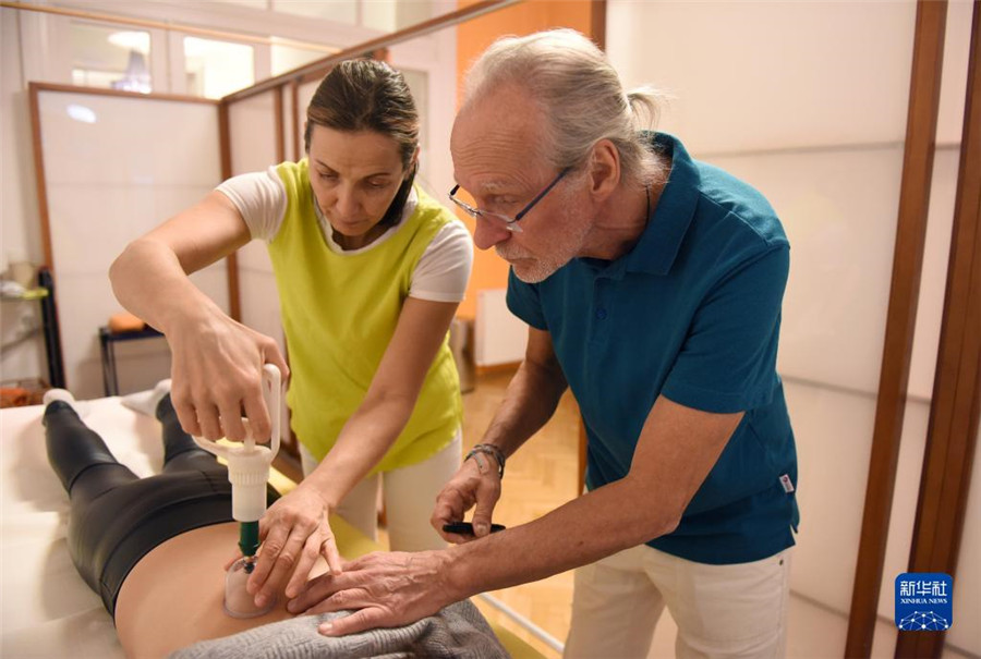 12月12日，在奧地利維也納，科格勒醫(yī)生（右）和助手在為病人進行拔罐治療。新華社記者 賀燦鈴 攝