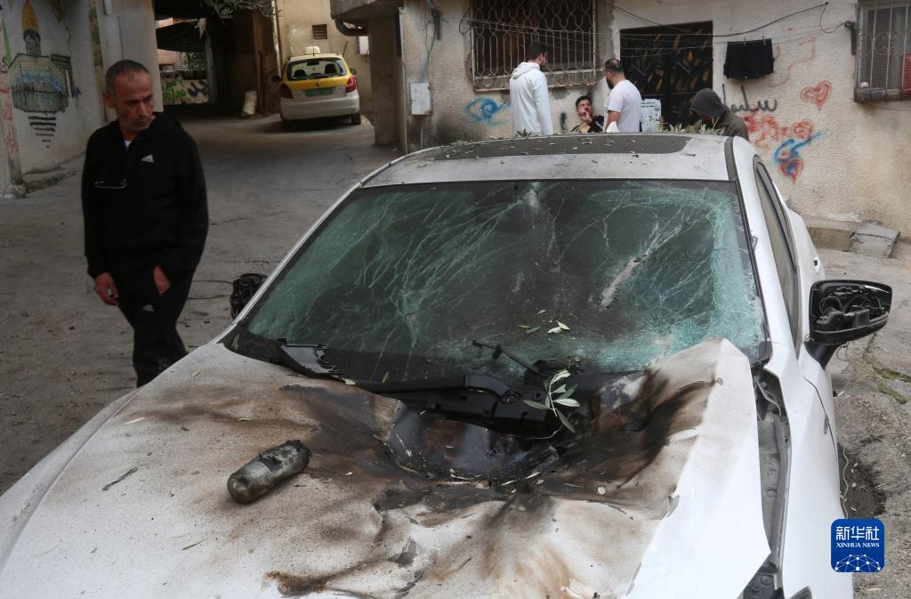 12月17日，在約旦河西岸城市圖勒凱爾姆附近的一處難民營，人們查看在沖突中損毀的車輛。新華社發(fā)（尼達(dá)爾·艾仕塔耶?dāng)z）