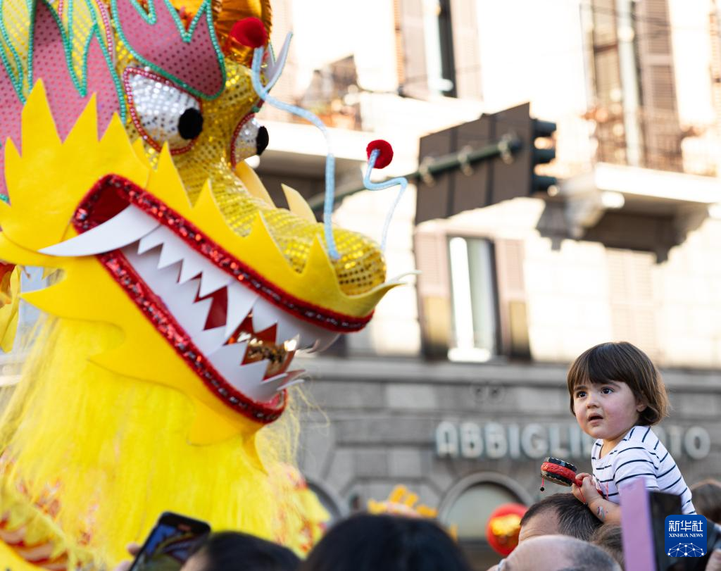 2月18日，在意大利羅馬，一名小朋友在彩妝巡游上觀看舞龍。新華社記者 李京 攝