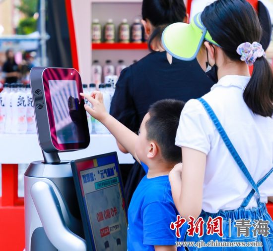 圖為一名小朋友正在和機(jī)器人“志愿者”進(jìn)行互動(dòng)。 沐聞 攝