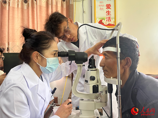 王紅英（左）和團(tuán)隊(duì)成員為達(dá)熱村村民檢查眼睛。人民網(wǎng)記者 杜燕飛攝