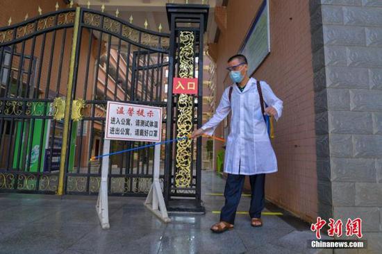 資料圖：海口經(jīng)濟(jì)學(xué)院的工作人員在學(xué)生宿舍樓入口消毒。 中新社記者 駱云飛 攝