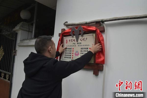 桂溪鎮(zhèn)渭溝村政府工作人員為“十星級文明戶”掛上牌匾。　楊勇 攝