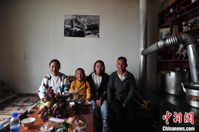 圖為8月12日，2018年7月從距那曲市色尼區(qū)城區(qū)那曲鎮(zhèn)90千米外的古露鎮(zhèn)當(dāng)桑村搬遷至城區(qū)的旦增(右一)與家人在80多平方米的新家合影(資料圖)。　張偉 攝