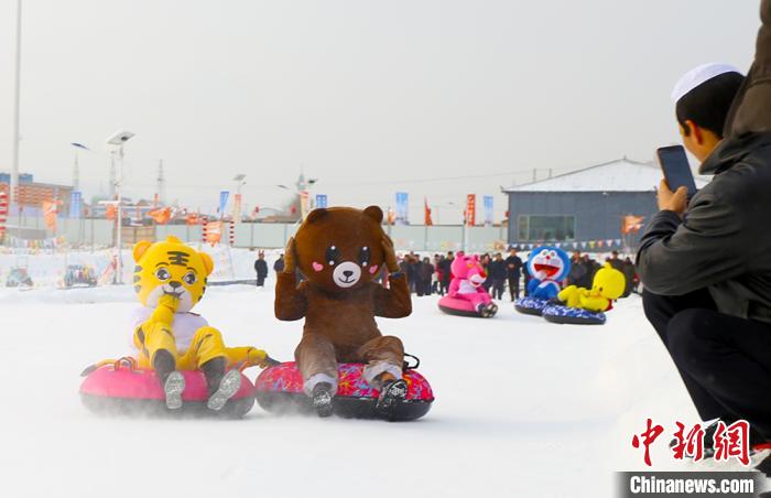 圖為臨夏市南龍鎮(zhèn)馬家莊村舉辦的鄉(xiāng)村文化旅游節(jié)上，游客穿著卡通服裝在體驗雪上飛碟項目。近年來，臨夏州形成了“春賞花、夏避暑、秋摘果、冬玩雪”的全季節(jié)旅游產(chǎn)品體系。(資料圖) 高展 攝