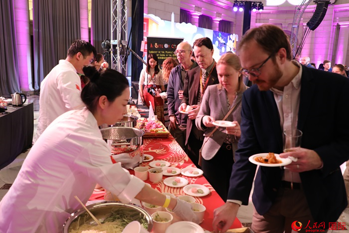 當(dāng)?shù)貢r(shí)間3月7日晚，華盛頓聯(lián)合車站廣場(chǎng)舉行駐美使團(tuán)“使館主廚挑戰(zhàn)賽”。圖為當(dāng)?shù)孛癖娫谥袊古_(tái)前體驗(yàn)中國美食。人民網(wǎng)記者 李志偉攝