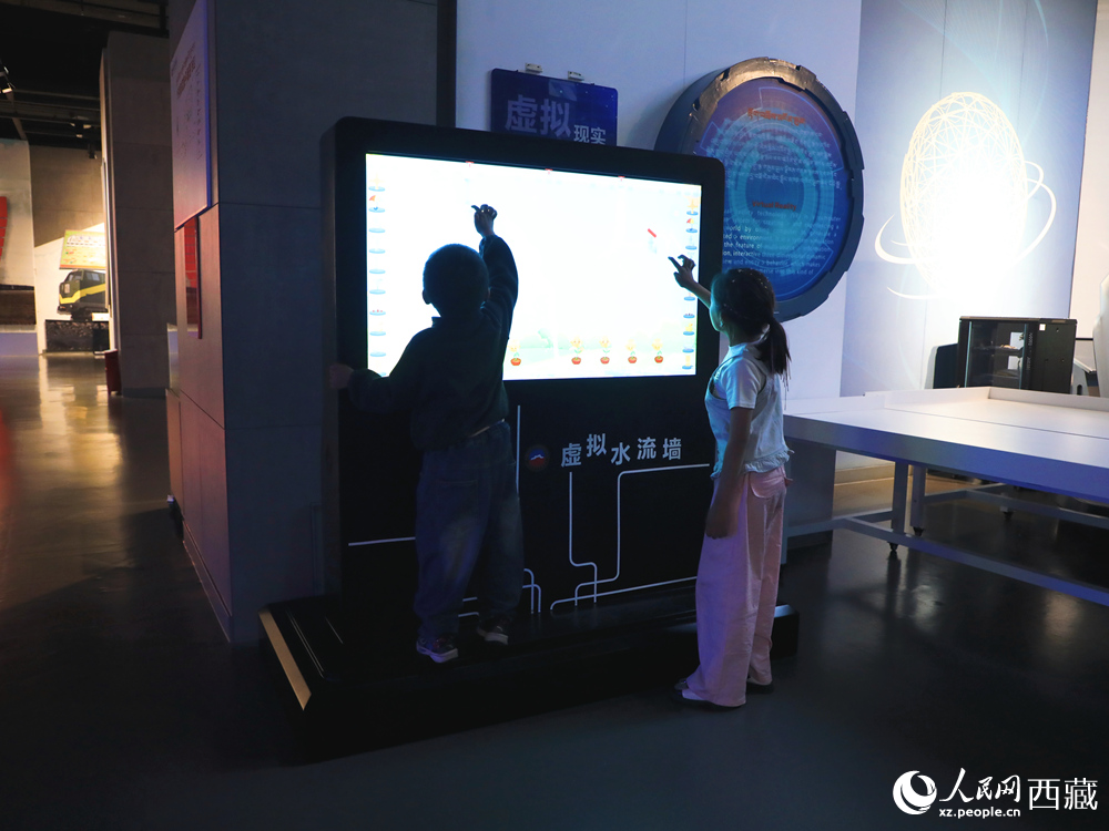 在西藏自然科學博物館科技館的互動展區(qū)，孩子們正全神貫注地體驗“虛擬水流墻”，探索流體力學帶來的視覺奇觀與科學樂趣。人民網(wǎng)記者 次仁羅布攝