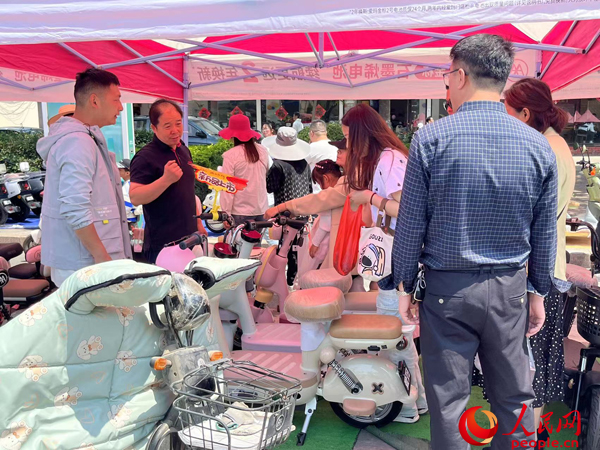 某電動(dòng)自行車(chē)品牌工作人員向消費(fèi)者介紹以舊換新相關(guān)情況。人民網(wǎng)記者 杜燕飛攝