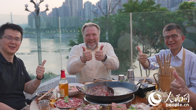 康寧顯示科技事業(yè)部全球拓建項(xiàng)目總監(jiān)軻寶華（中）和同事在重慶南濱路吃火鍋。人民網(wǎng)記者 蘇纓翔攝