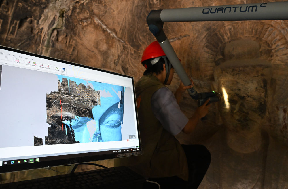 2025年4月9日，武漢大學(xué)文化遺產(chǎn)智能計(jì)算實(shí)驗(yàn)室團(tuán)隊(duì)成員在魏字洞使用關(guān)節(jié)臂掃描儀對(duì)佛像進(jìn)行數(shù)字化掃描。圖片來(lái)源新華社