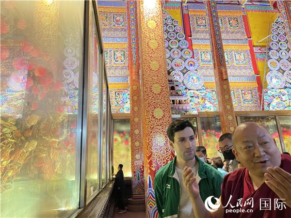 7月25日，省級非物質(zhì)文化遺產(chǎn)項目塔爾寺酥油花的代表性傳承人朋措堅參（右）在塔爾寺酥油花館講解酥油花的制作過程。人民網(wǎng) 謝瑩攝