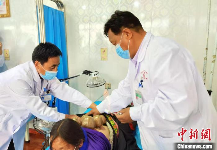 圖為看照加手把手帶徒弟加老(左一)進行拔罐療法。　張婧 攝