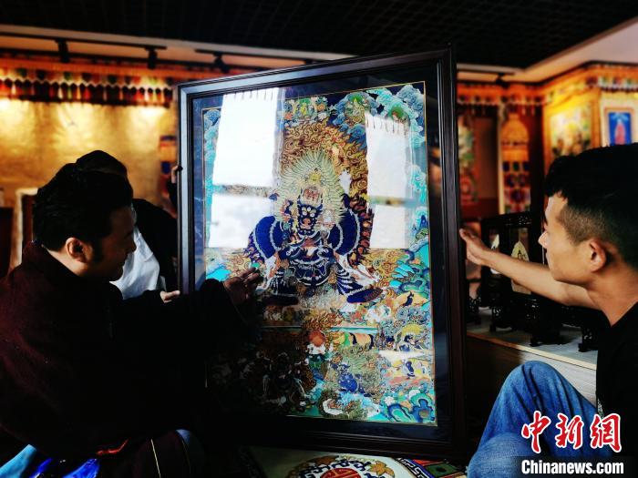 圖為久美尖措(左)與徒弟們展示唐卡作品?！?zhí)砀?攝