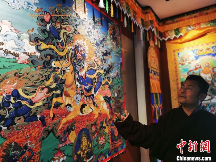 圖為久美尖措展示唐卡作品?！?zhí)砀?攝