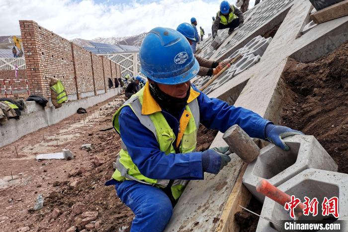 圖為光伏發(fā)電項(xiàng)目施工區(qū)工人在護(hù)坡鋪設(shè)空心磚。　李雋 攝