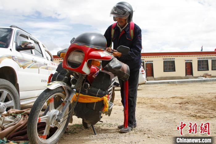 圖為白瑪準(zhǔn)備騎摩托車巡湖?！≮w朗 攝