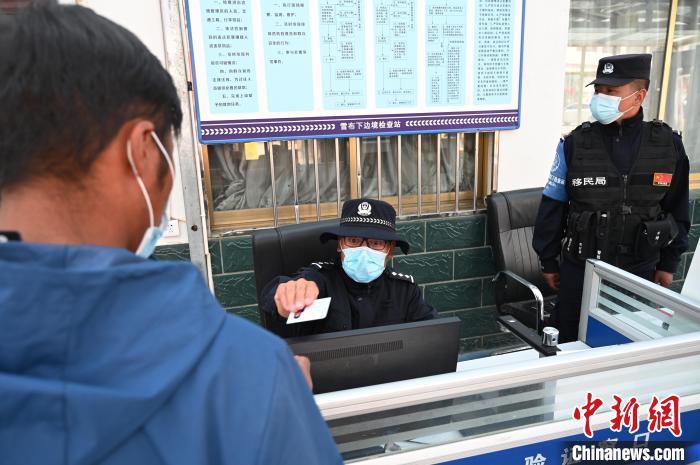 圖為移民管理警察登記完身份信息后將證件歸還給行人?！≮w朗 攝