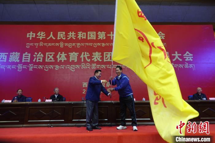 西藏自治區(qū)副主席甲熱·洛桑丹增授代表團(tuán)團(tuán)旗，西藏自治區(qū)體育局局長(zhǎng)尼瑪次仁接旗?！∪轿木?攝