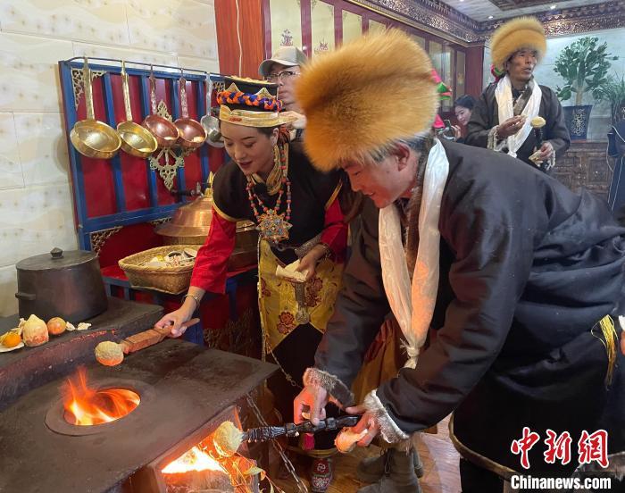 圖為人們在火上烤節(jié)日美食“結達”?！∪轿木?攝