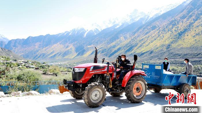 圖為工作人員將把加工完成的糌粑運送至村民手中?！〖卫杩h融媒體中心供圖