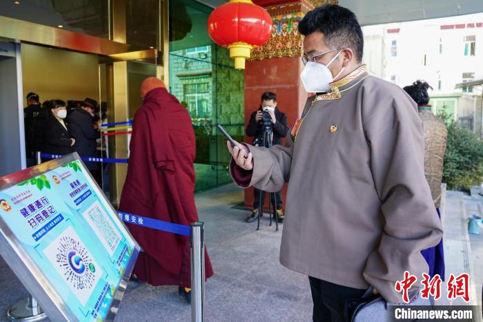 圖為政協(xié)委員掃場所碼進入會場。　江飛波 攝