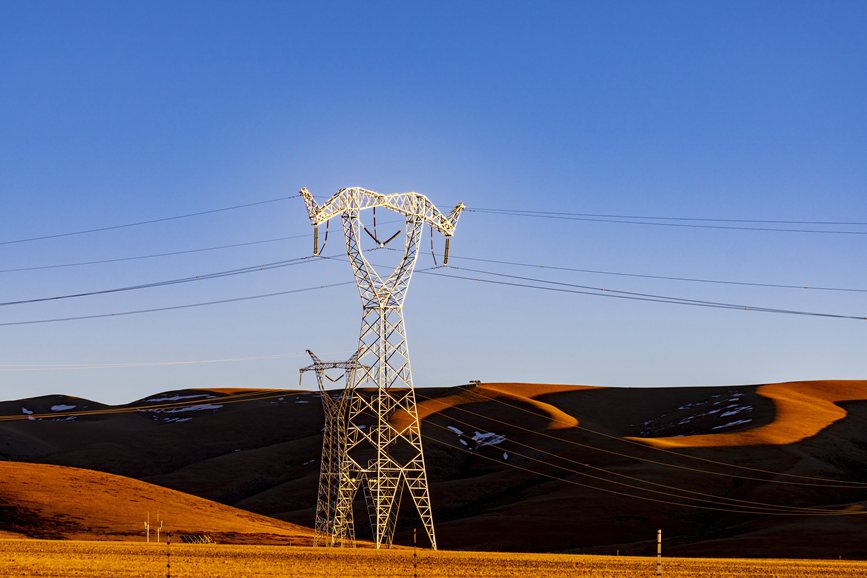 阿里地區(qū)的曠野上，電力鐵塔在夕陽(yáng)下熠熠生輝。