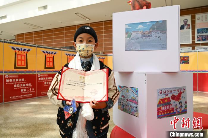 圖為一名獲獎(jiǎng)學(xué)生與自己的繪畫作品合影?！≮w朗 攝