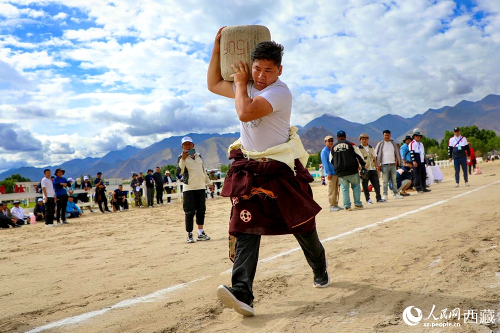 來自拉薩市當(dāng)雄縣的牧民選手將一塊150斤重的石頭扛在肩上飛奔。