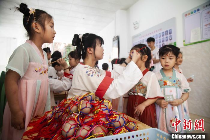 圖為幼兒園的老師們穿上漢服為小朋友們戴上彩蛋，寓意著幸福安康?！《^生 攝