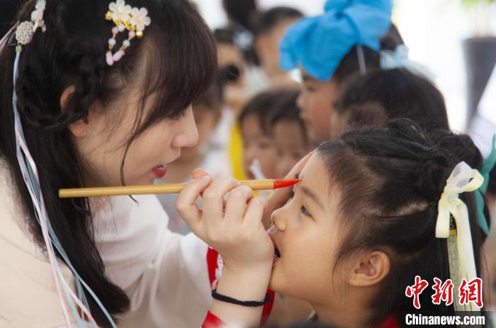 圖為老師在孩子們額頭上點(diǎn)上雄黃，驅(qū)邪辟禍?！《^生 攝